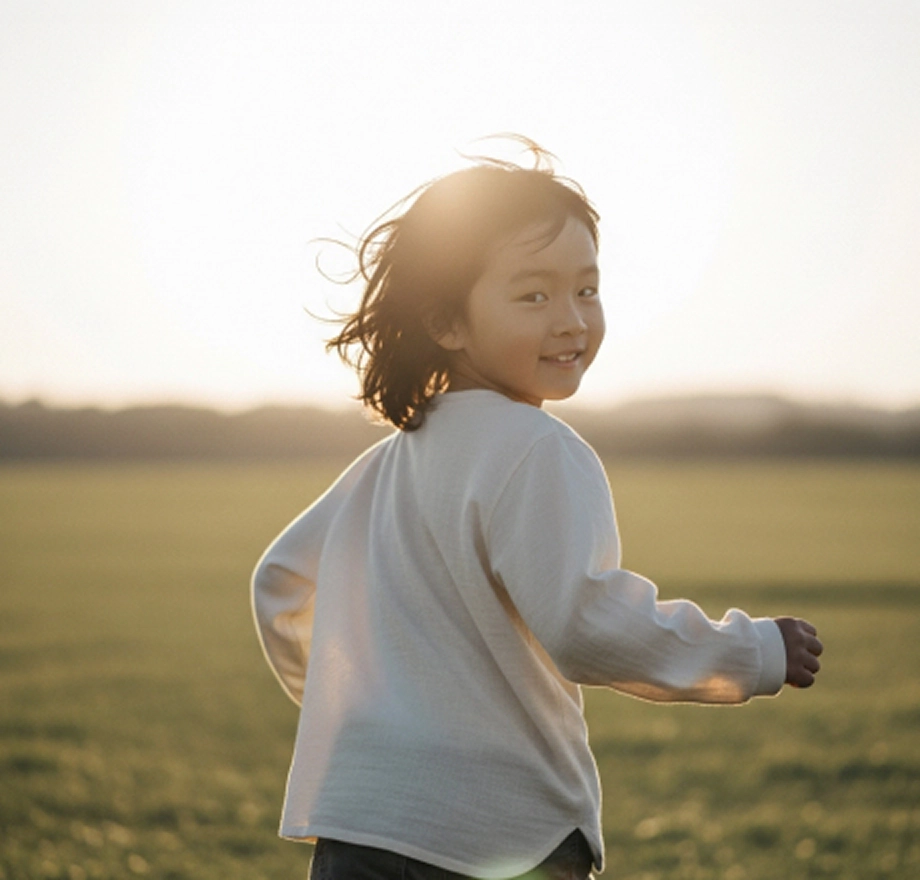 들판을 달리다 뒤를 바라보는 남자 아이
